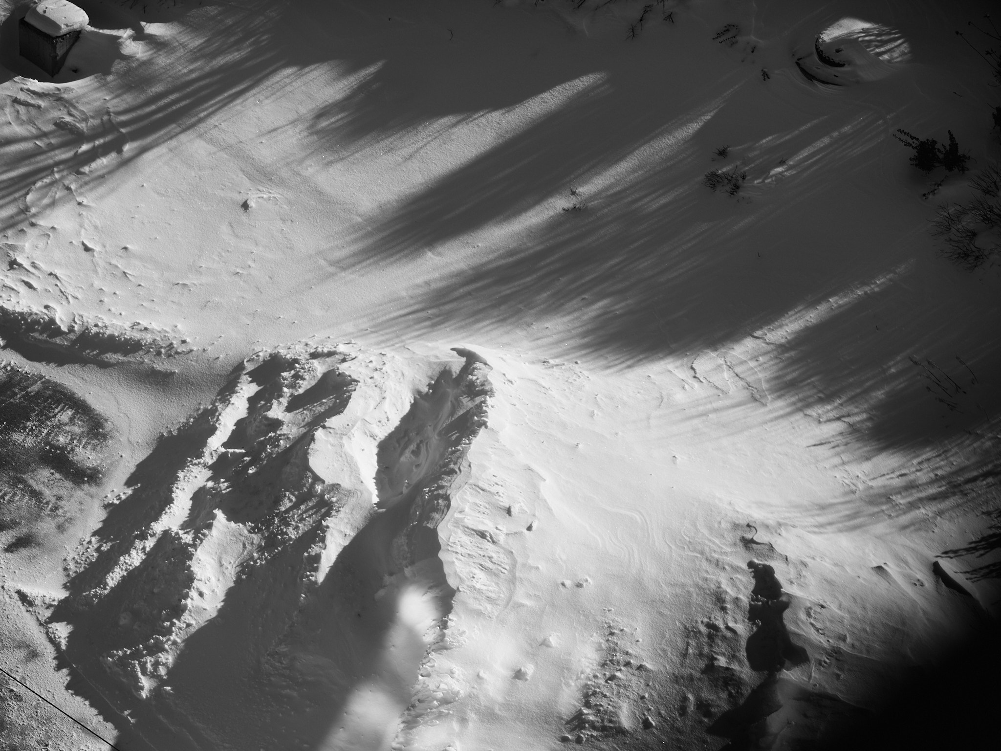 Sloping snowbank with shadow streaks and a rocky outcrop