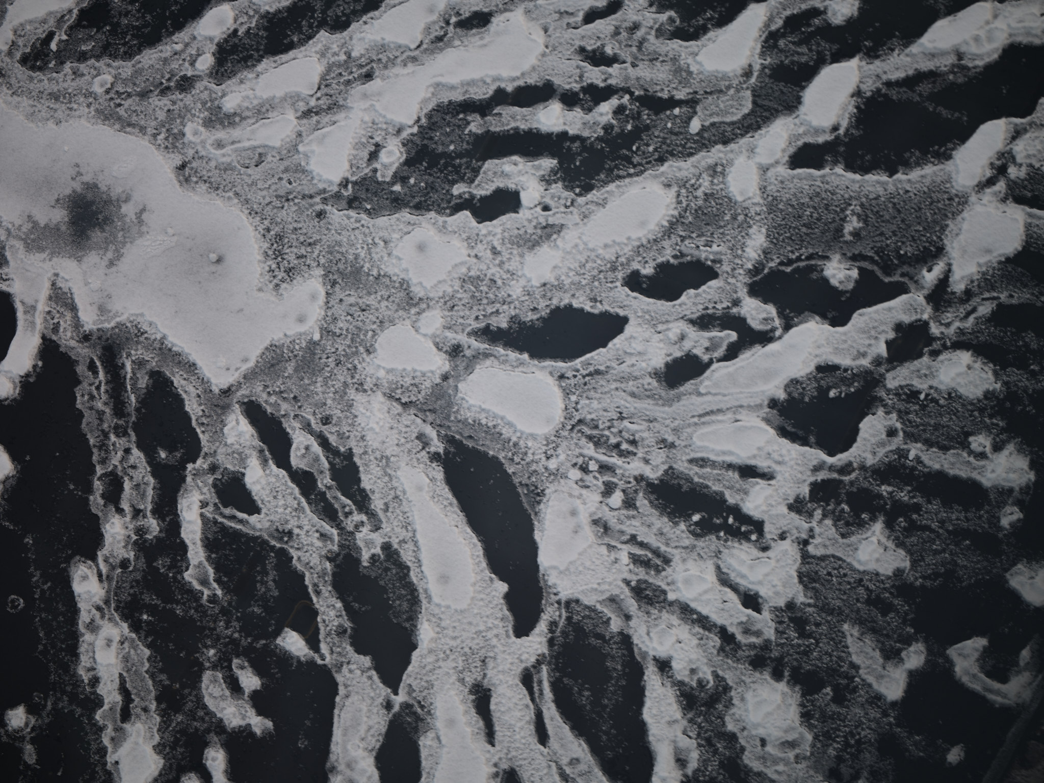 Irregular islands of snow scattered across a dark field, like an archipelago